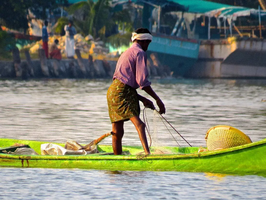 Pescador de pé numa canoa, recolhendo a rede