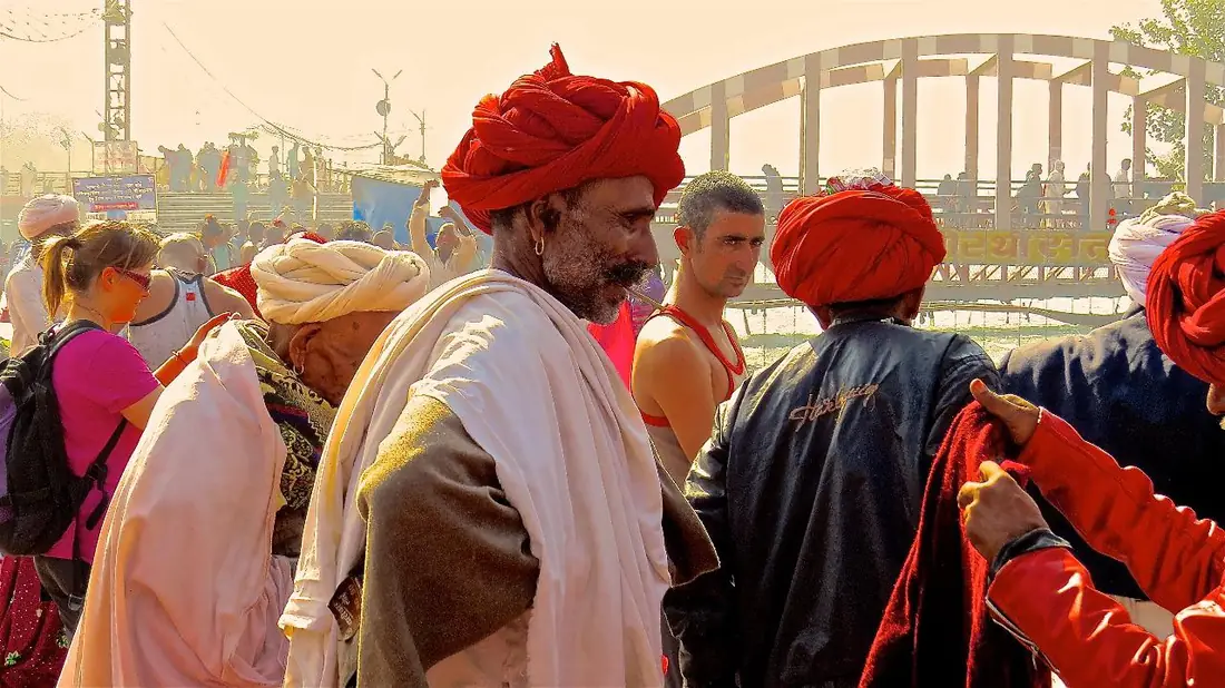 Homens de turbante vermelho reunidos junto a uma ponte