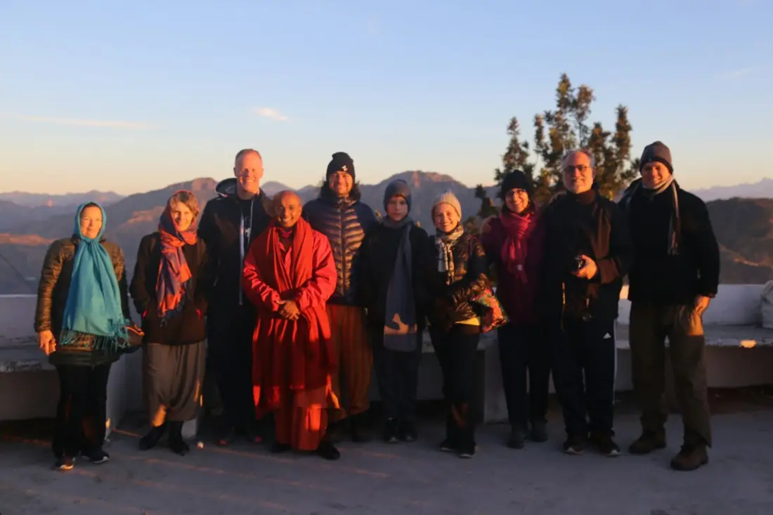 Grupo de viajantes reunido ao amanhecer, com montanhas ao fundo